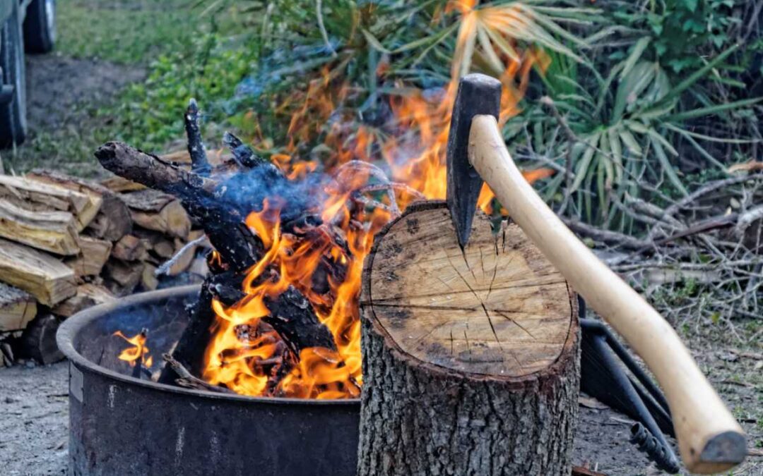 Hache plantée dans un tronc d'arbre avec un feu qui brûle en arrière-plan